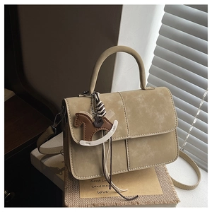 Detail view of khaki PU leather handbag with a unique horse charm in natural light