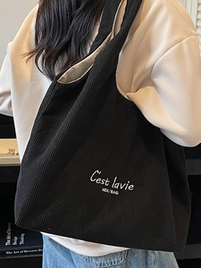 Grande borsa tote in velluto a coste nero con ricamo indossata da modella in una biblioteca