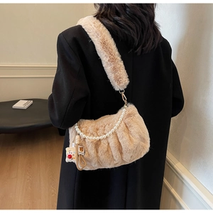 Détail du sac en peluche avec chaîne de perles et breloque sur manteau noir