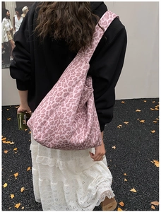 Detail of pink leopard print tote bag with wide strap on a female model with white skirt
