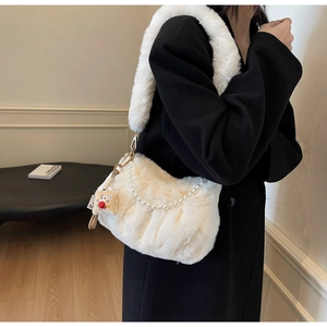 Gros plan du sac bandoulière en fausse fourrure pelucheuse blanche avec chaîne de perles