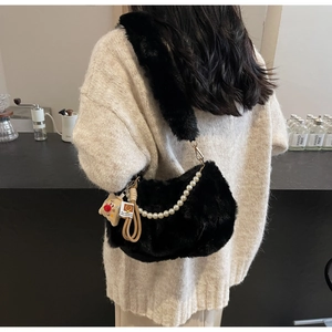 Détail du sac à bandoulière en peluche noire avec chaîne perlée et texture douce