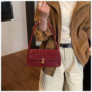 Detail view of red leopard print underarm bag with metal buckle on a shoulder strap