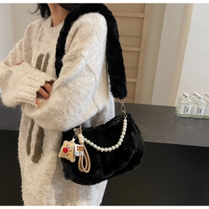 Détail du sac à bandoulière en peluche noire avec chaîne de perles et pendentif poupée