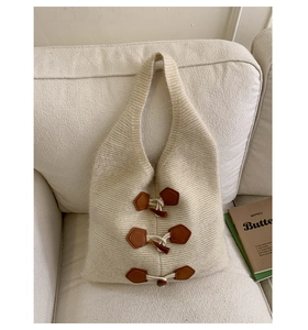 Texture détaillée du sac cabas en tricot blanc cassé avec boutons brandebourg marron