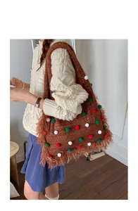 Brown woven knit tote bag featuring colorful pompoms and fringe details on model