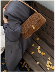 Close-up of leopard print shoulder bag with metal lock worn with autumn outfit