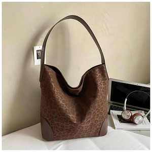 Detail of leopard print tote bag with brown leather reinforcement and soft matte texture