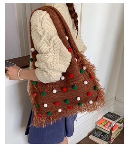 Detail of a brown knitted tote bag with festive red white and green pompoms and fringe