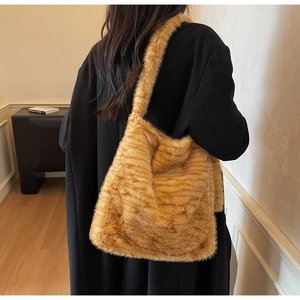 Detailed view of large plush tote bag in orange-brown striped faux fur on female model