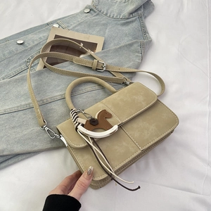 Detail view of khaki square bag with accordion side folds and leather horse charm