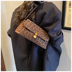 Close-up of leopard print shoulder bag with gold metal lock on striped blazer outfit