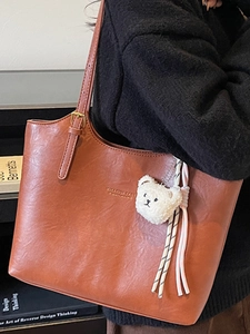 Brown minimalist PU leather tote bag with gold logo and plush bear charm for daily commute