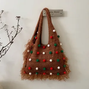 Détail d'un sac à bandoulière en tricot marron avec pompons et longues franges