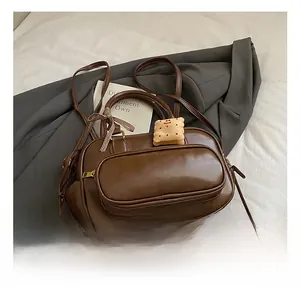 Détail d'un sac cabas marron foncé avec ruban à carreaux et pendentif biscuit en peluche
