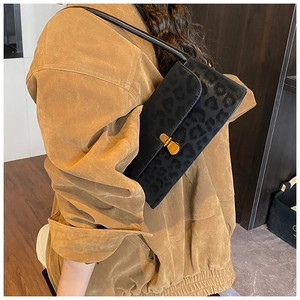 Detail of black shoulder bag with leopard embossing and gold metal oval clasp