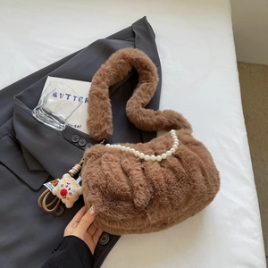 Gros plan sur un sac en peluche marron avec chaîne en perles et pendentif ourson