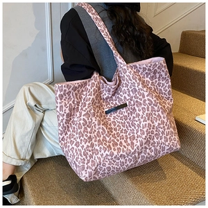 Detail of pink leopard print tote bag with black logo patch and durable canvas texture