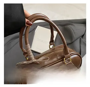 Détail du sac Boston en PU marron avec un nœud en ruban à carreaux et un pendentif peluche toast