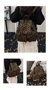 Detail view of leopard print canvas backpack showing drawstring closure and red embroidery