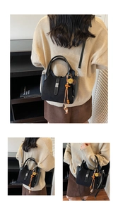 Detail of black matte and glossy handbag with wooden beads and tassel charms
