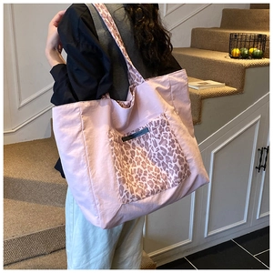 Detail of a pink canvas tote bag with a leopard print pocket and matching straps