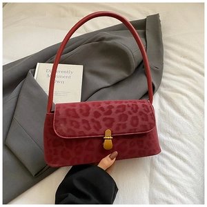 Detail shot of red leopard print baguette bag with golden clasp on grey suit jacket