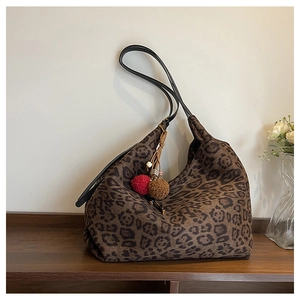 Detail of leopard print tote bag with soft texture and decorative pom-pom pendant