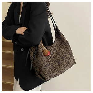 Detail of leopard print hobo tote bag with pom-pom pendant and black shoulder straps