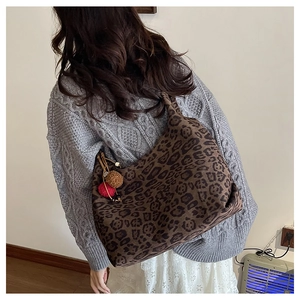 Detailed view of leopard print canvas tote bag with decorative red and brown pompoms