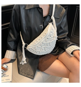 Detail of white handmade woven crescent bag featuring long tassels and cotton rope texture