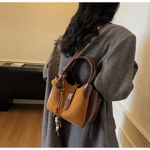 Detailed close-up of retro brown bucket bag with contrast leather and long tassel