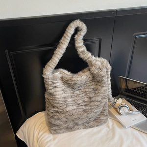 Detail view of striped faux fur tote bag with plush texture on soft white bedding
