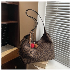 Detail of leopard print hobo tote bag with long leather strap and plush pompom charms