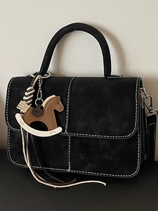 Black matte handbag with contrast stitching and a rocking horse charm ornament