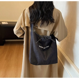 Détail du sac cabas en denim bleu foncé avec noeud et texte Bonne journée blanc
