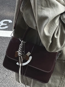 Elegant burgundy leather messenger bag with white stitching and horse charm for women