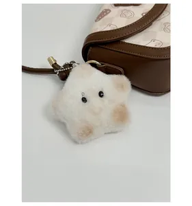 Detail of plush star-shaped pendant with metal clasp on a stylish brown vintage bag