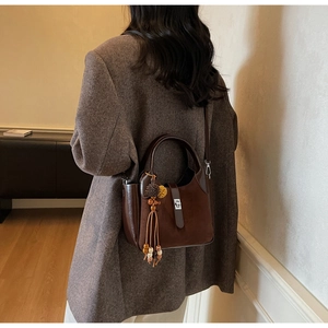 Detail of a dark brown suede bucket bag featuring elegant wood bead charms and metal lock
