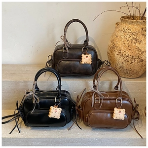 Trois sacs Boston en cuir noir et marron avec rubans et breloques de biscuits