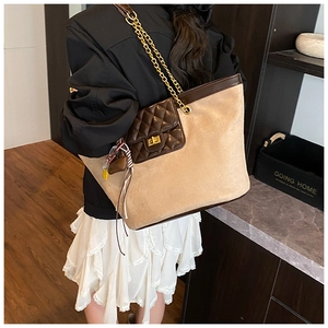 Detail of beige suede tote bag with brown quilted pocket, gold chain strap and colorful tassel