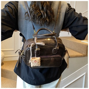 Sac à main marron en similicuir avec ruban vintage et breloque peluche porté par modèle