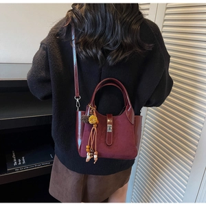 Detail of burgundy bucket bag with bead tassel charm and mixed leather textures