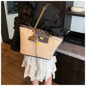 Detail of a large beige suede tote with brown quilted pocket and gold chain strap