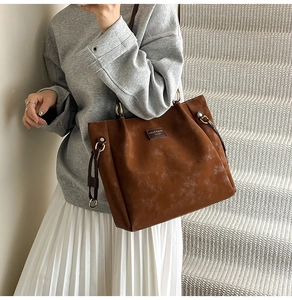 Close-up of caramel tote bag with brown leather straps and gold metal ring detail