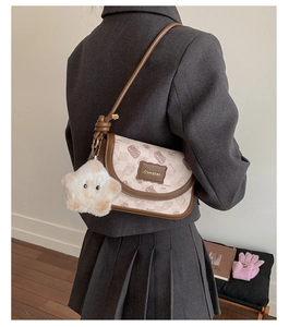 Detail of printed crossbody bag featuring Bread Cat motif and plush star charm on model