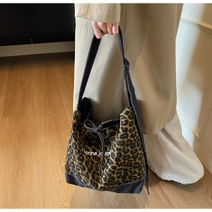 Détail du sac cabas en toile imprimé léopard avec poignée en patchwork de denim bleu marine