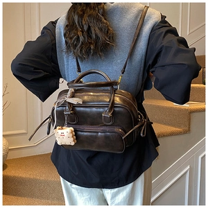 Détail d'un sac bandoulière vintage marron foncé avec nœud en ruban et breloque peluche