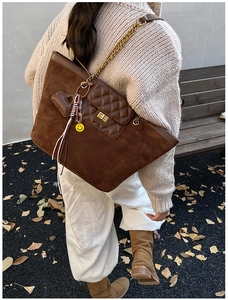 Detail of a brown suede tote bag with quilted leather pocket and golden chain strap