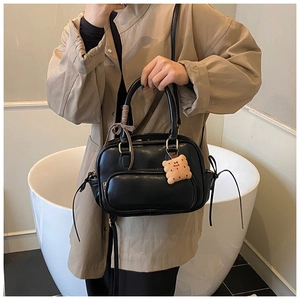 Détail du sac à main en cuir PU noir mat avec ruban rayé et breloque en peluche